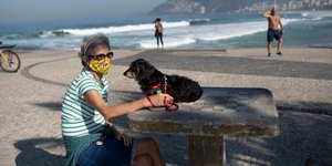 Γυναίκα με το σκυλί της στην παραλία, φορώντας μάσκα για τον κορωνοϊό