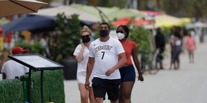 Αμερικανοί περπατούν σε δρόμο στην Φλόριντα φορώντας μάσκα για τον κορωνοϊό