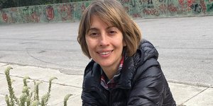 Η Βίκυ Βολιώτη κάθεται και φοράει μπλε μπουφάν