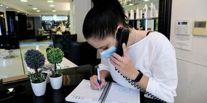 Υπάλληλος σε κομμωτήριο μιλάει στο τηλέφωνο και κρατά σημειώσεις