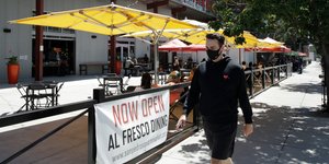 Ανδρας με μάσκα περπατά έξω από εστιατόριο στην Καλιφόρνια