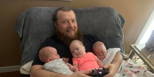 Ανδρας κρατάει αγκαλιά τρίδυμα 