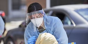 Ειδικός με μάσκα και προστατευτικό πραγματοποιεί τεστ για τον κορωνοϊό