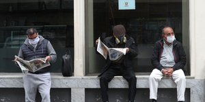 Εργάτες στο Περού διαβάζουν εφημερίδα φορώντας μάσκα για τον κορωνοϊό