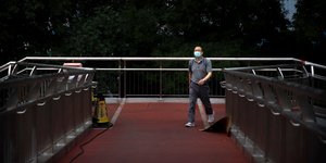 Κινέζος περπατά σε γέφυρα φορώντας μάσκα για τον κορωνοϊό