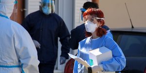 Γιατρός με ειδική στολή και μάσκα για τον κορωνοϊό, κουβαλά πράγματα