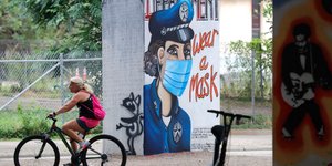 Ποδηλάτρια στο Ντάλας περνά δίπλα από γκράφιτι με αστυνομικό που φορά μάσκα