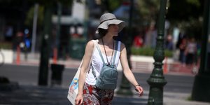 Γυναίκα περπατά φορώντας καπέλο για τη ζέστη