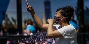 Γυναίκα βγάζει φωτογραφίες με το κινητό, φορώντας μάσκα για τον κορωνοϊό