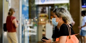 Γυναίκα με μάσκα για τον κορωνοϊό και πορτοκαλί τσάντα