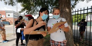 Γυναίκες κρατούν σημειώσεις περιμένοντας για τεστ κορωνοϊού