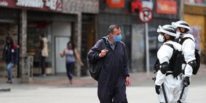 Κολομβιανός μιλάει με στρατιώτες που φορούν ειδικές στολές και μάσκες