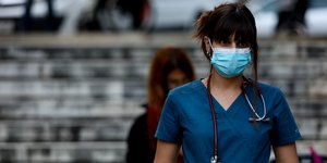 Κορωνοϊός: Μια νοσηλεύτρια με μάσκα παρακολουθεί ομιλία