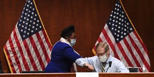 άντρας και γυναίκα με μάσκες μπροστά από αμερικανικές σημαίες