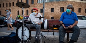 Ανδρας παίζει ντραμς σε παγκάκι στο Τελ Αβίβ φορώντας μάσκα για τον κορωνοϊό