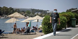Ανδρας περπατά σε παραλία με μάσκα για κορωνοϊό