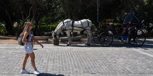 Πεζή περνά δίπλα από καρότσα με άλογο στο Θησείο