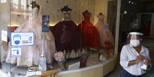 Γυναίκα με μάσκα και προστατευτικό ενάντια στον κορωνοϊό σε βιτρίνα καταστήματος του Μεξικού