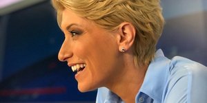 Η Σία Κοσιώνη με κοντομάνικο πουκάμισο χαμογελά