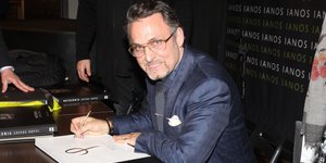 Ο Σπύρος Πώρος με μπλε κοστούμι υπογράφει βιβλίο