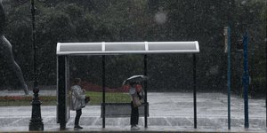 Γυναίκες σε στάση λεωφορείου κρύβονται από την βροχή