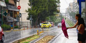 Κοπέλες περιμένουν στη στάση του τραμ κάτω από βροχή