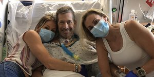 Ο 54χρονος Γκρεγκ Γκάρφιλντ στο κρεβάτι του νοσοκομείου με την αδερφή του (αριστερά) και τη σύντροφό του (δεξιά) 