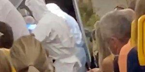 Ανδρες με προστατευτικές στολές απομακρύνουν επιβάτη αεροπλάνου με κορωνοϊό