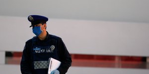 Αστυνομικός με ντοσιέ και μάσκα για τον κορωνοϊό