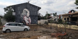 Αυτοκίνητο στις λάσπες δίπλα σε σπίτι με γκράφιτι