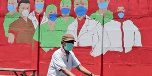 Άνδρας με μάσκα μπροστά από γκράφιτι με γιατρούς και νοσοκόμους