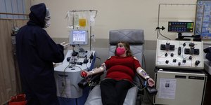 Γυναίκα με μάσκα προστασίας από τον κορωνοϊό δίνει πλάσμα