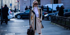 Γυναίκα με μπεζ κοστούμι, γυαλιά, τσάντα, λευκές μπότες 