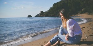 Γυναίκα με τζιν και λευκό πουκάμισο στην παραλία