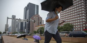 Κινέζος με μάσκα και ομπρέλα περπατάει