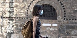 Μια γυναίκα περπατά στην Ερμού φορώντας μάσκα