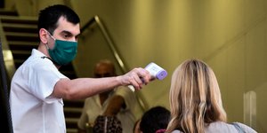 Άνδρας με μάσκα πραγματοποιεί θερμομέτρηση πριν την επιβίβαση στο πλοίο