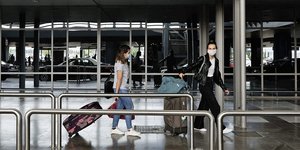 Ταξιδιώτες στο αεροδρόμιο Μακεδονία με βαλίτσες και μάσκες προστασίας από τον κορωνοϊό