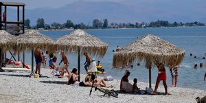 Ψάθινες ομπρέλες και κόσμος σε παραλία