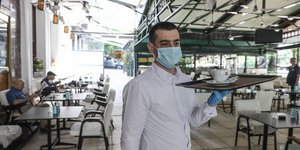 Σερβιτόρος με δίσκο φορά μάσκα για τον κορωνοϊό