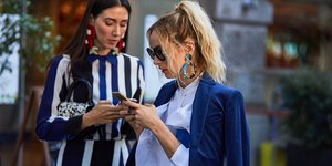 στιλάτες γυναίκες κοιτούν το κινητό τους