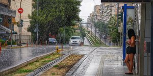 Κοπέλα κάθετε σε στάση του τραμ ενώ βρέχει