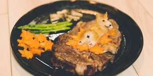 Μαύρο πιάτο με κρέας που είναι διακοσμημένο σαν έργο τέχνης