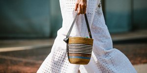 Γυναίκα με λευκό παντελόνι και ψάθινη τσάντα