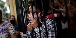 Γυναίκα στέκεται πίσω από καγκελόπορτα στην Βραζιλία