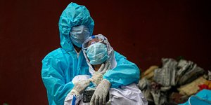 Ανδρας με ειδική στολή κρατά γυναίκα που θρηνεί