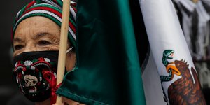 Ηλικιωμένη με μάσκα κρατά την μεξικάνικη σημαία