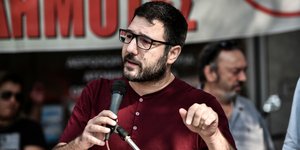 Ο Νάσος Ηλιόπουλος με μικρόφωνο και κόκκινη μπλούζα