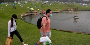 Κινέζοι με μάσκες και φαγητό στο χέρι περπατούν σε πάρκο