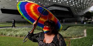 Γυναίκα με μάσκα και ομπρέλα στα χρώματα του ουράνιου τόξου